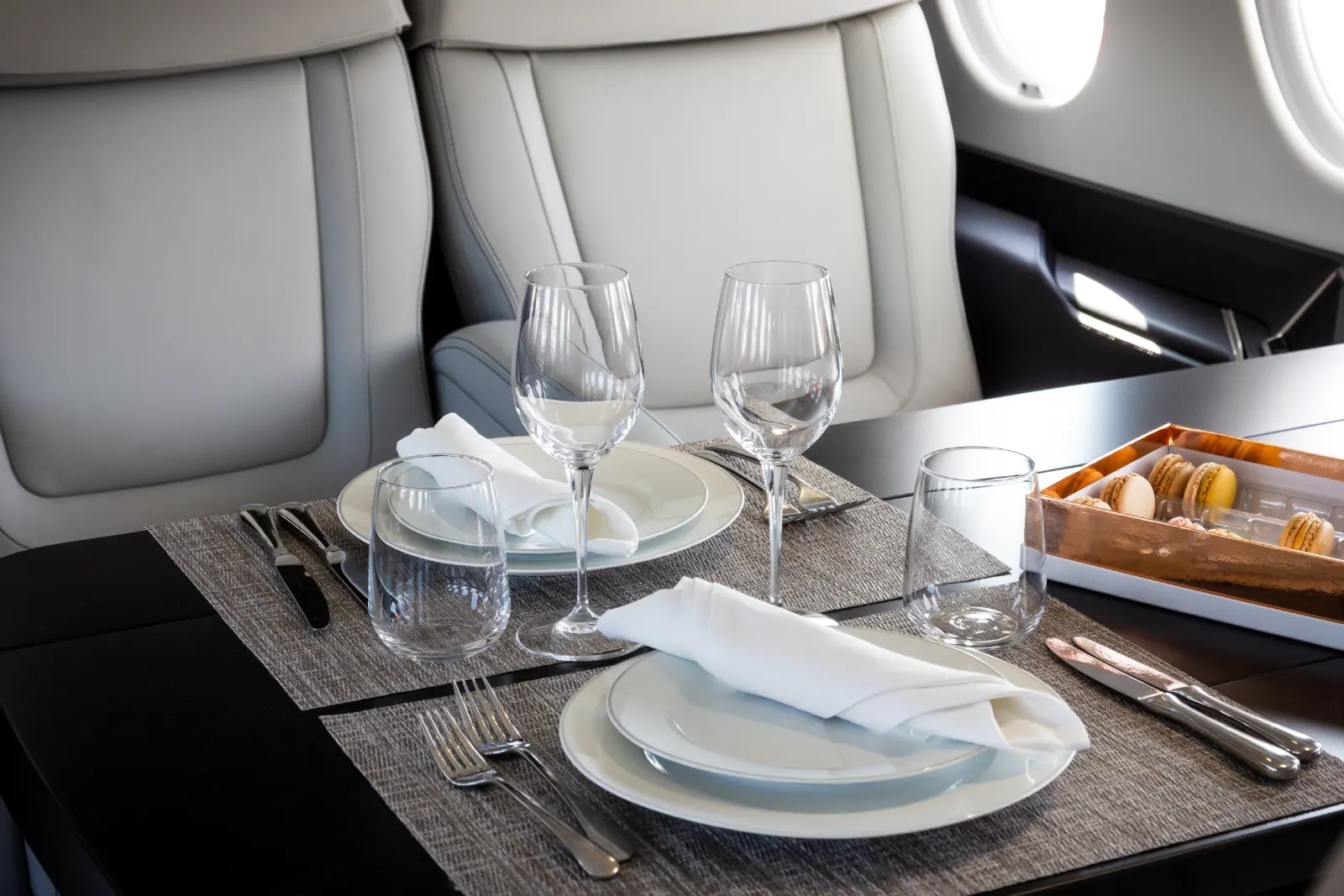 Cabine de jet privé : table dressée, vaisselle et macarons à bord