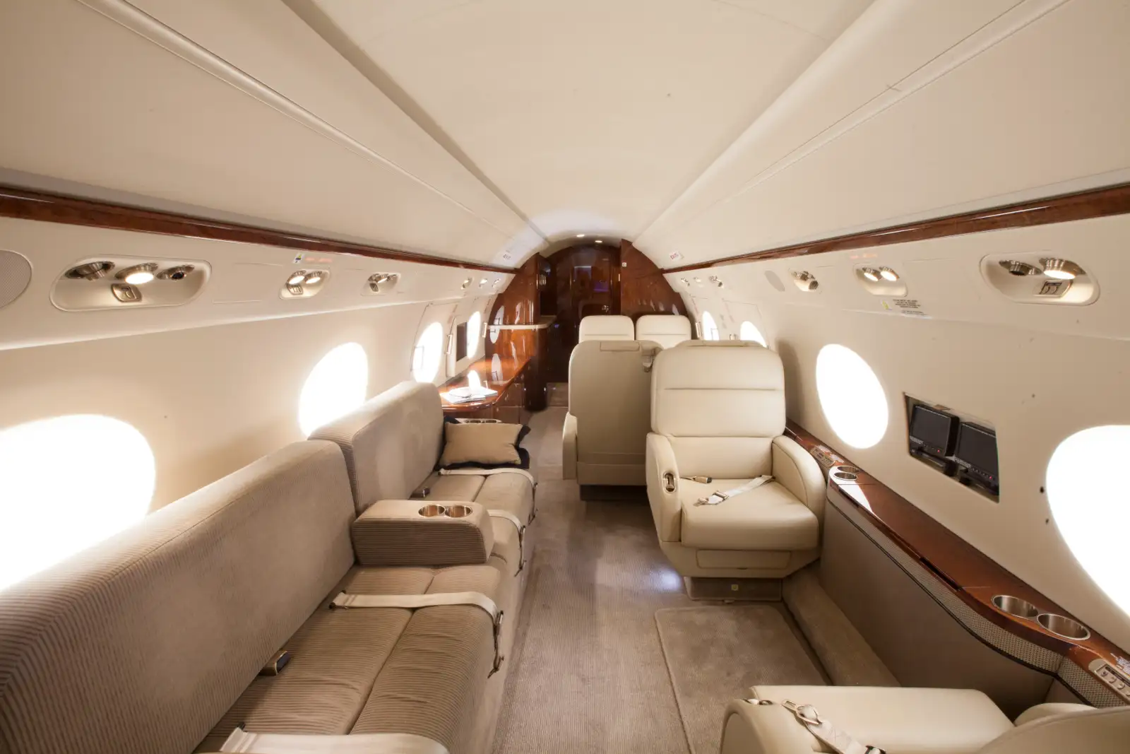 Jet privé : cabine en cuir crème et boiseries vernies d’un avion d’affaires