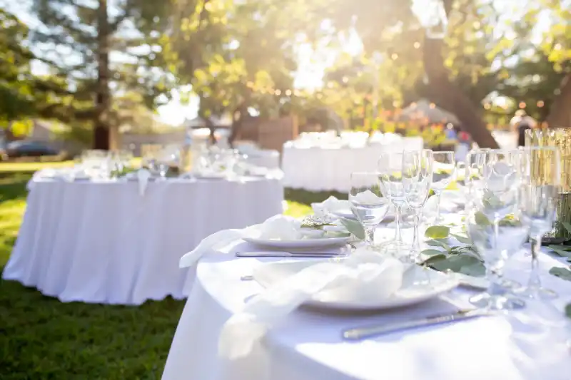 Mariage de luxe : tables dressées pour une réception dans un jardin au coucher du soleil